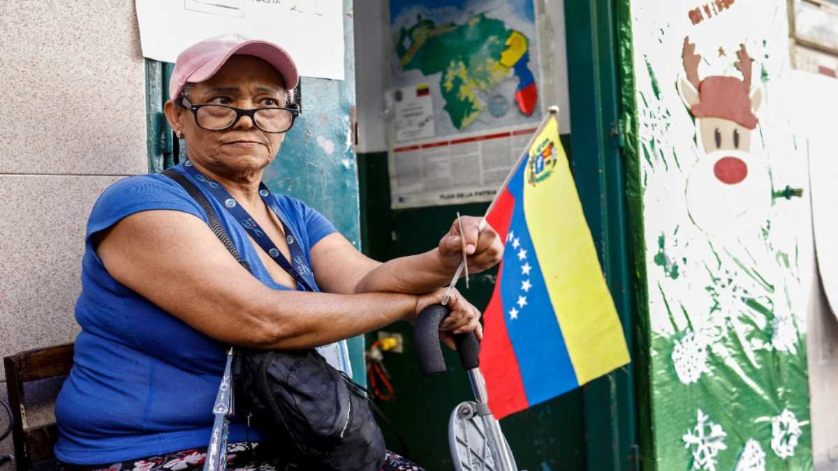 Una mujer ondea la bandera de Venezuela, en medio del referéndum sobre el territorio en disputa con Guyana. Foto: Pedro Rances Mattey / AFP.