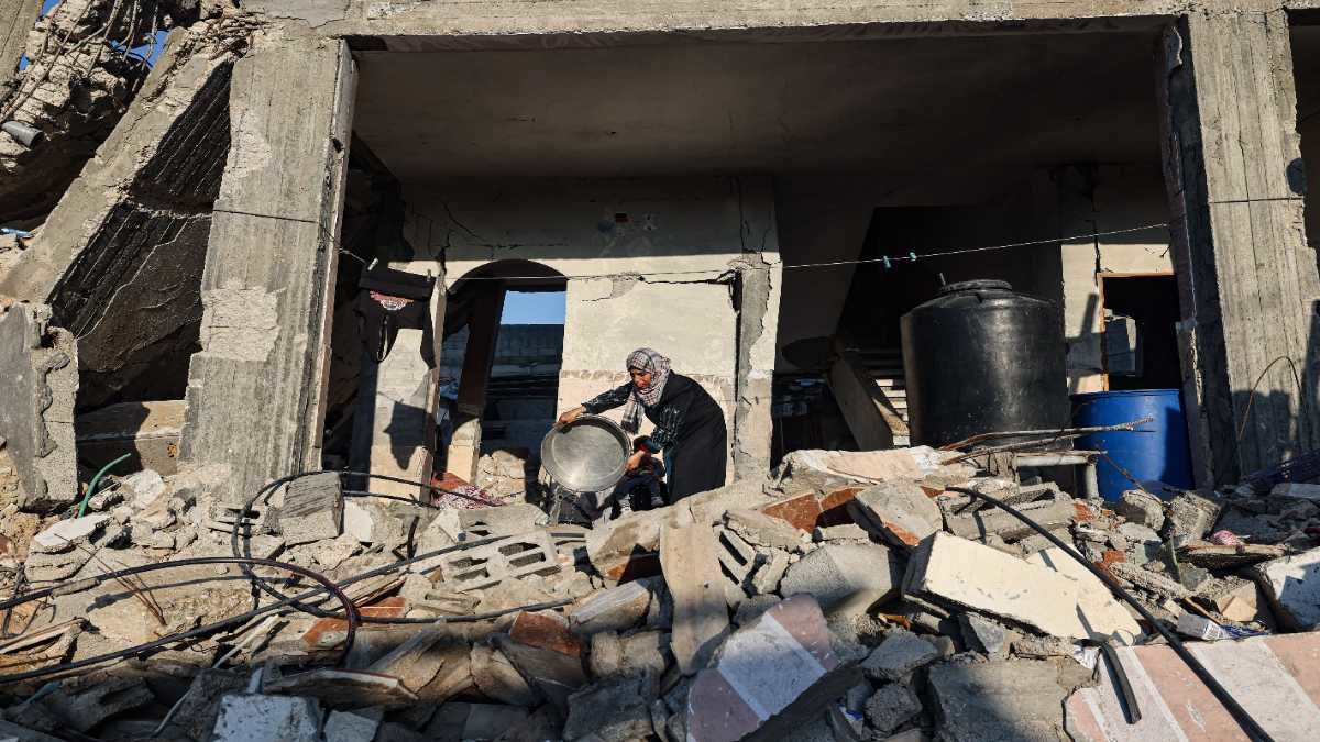 Una mujer lava en medio de las ruinas de su casa destruida como resultado de la guerra entre Israel y Hamas, en Gaza. Foto: Mohammed Abed / AFP.