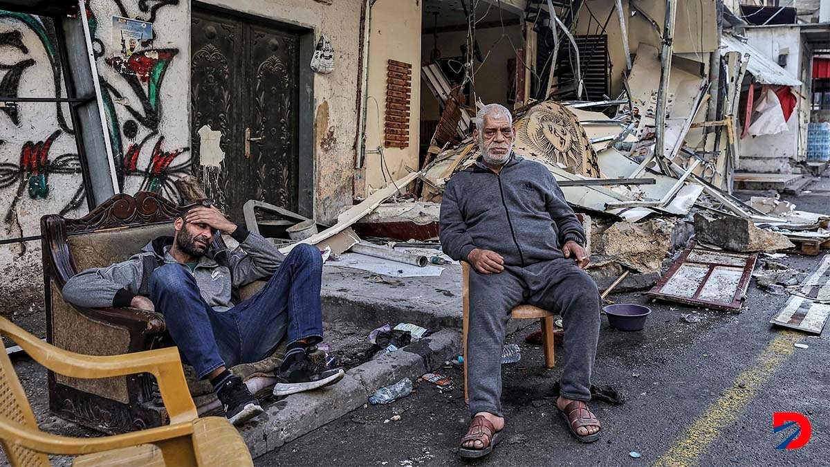 Algunos palestinos esperan a las afueras de las ruinas de lo que era un campo de refugiados, destruido por un bombardeo israelí esta semana. Foto: AFP.