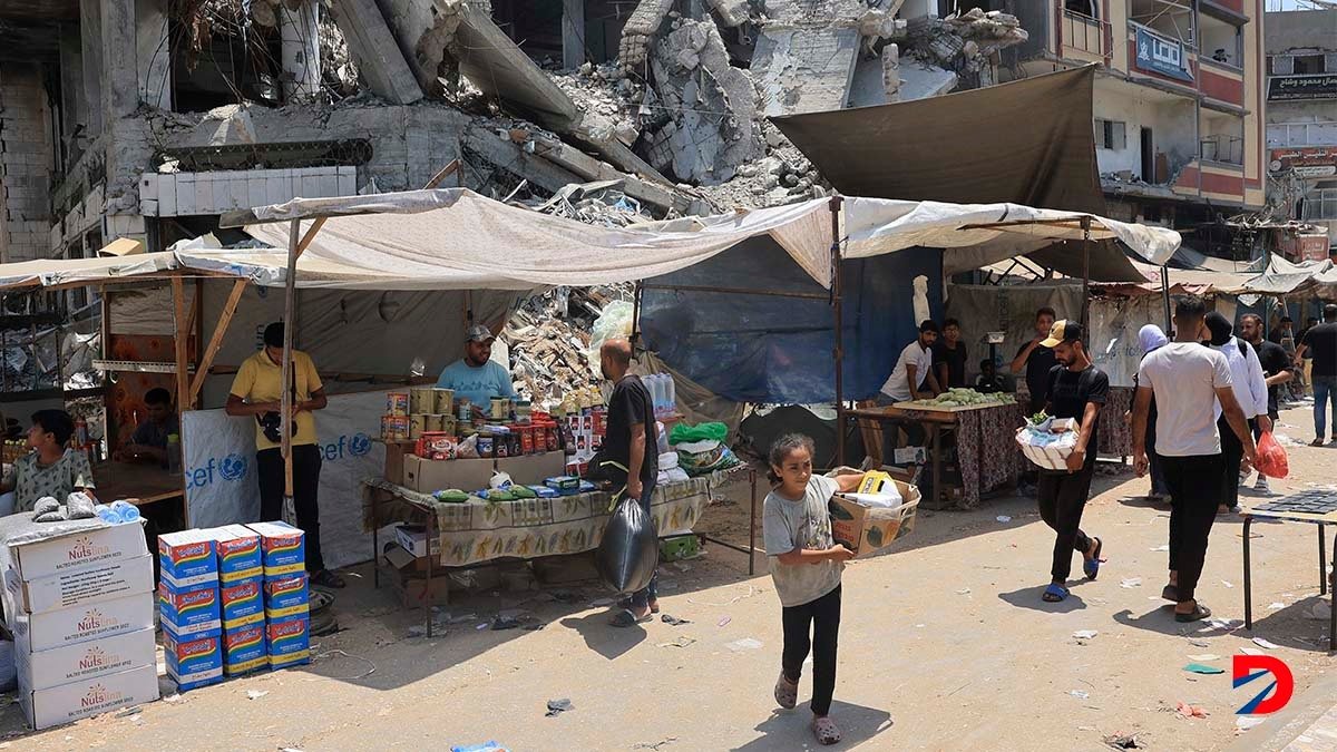 Algunas personas tratan de comprar productos básicos en una población del centro de Gaza, mientras la guerra sigue. Foto: Eyad Baba / AFP.